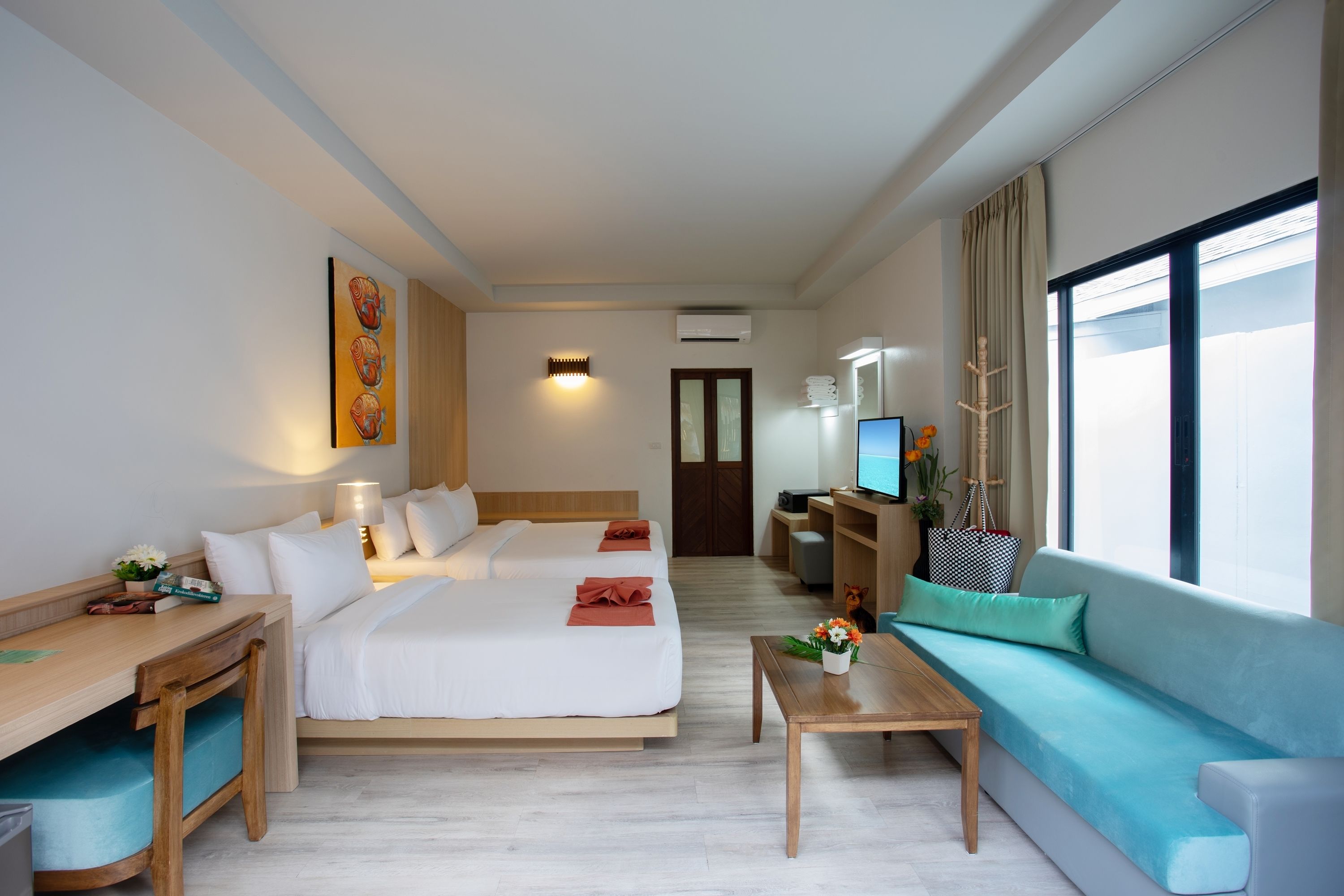 A hotel room with a large bed, a desk, a sofa, and a television.