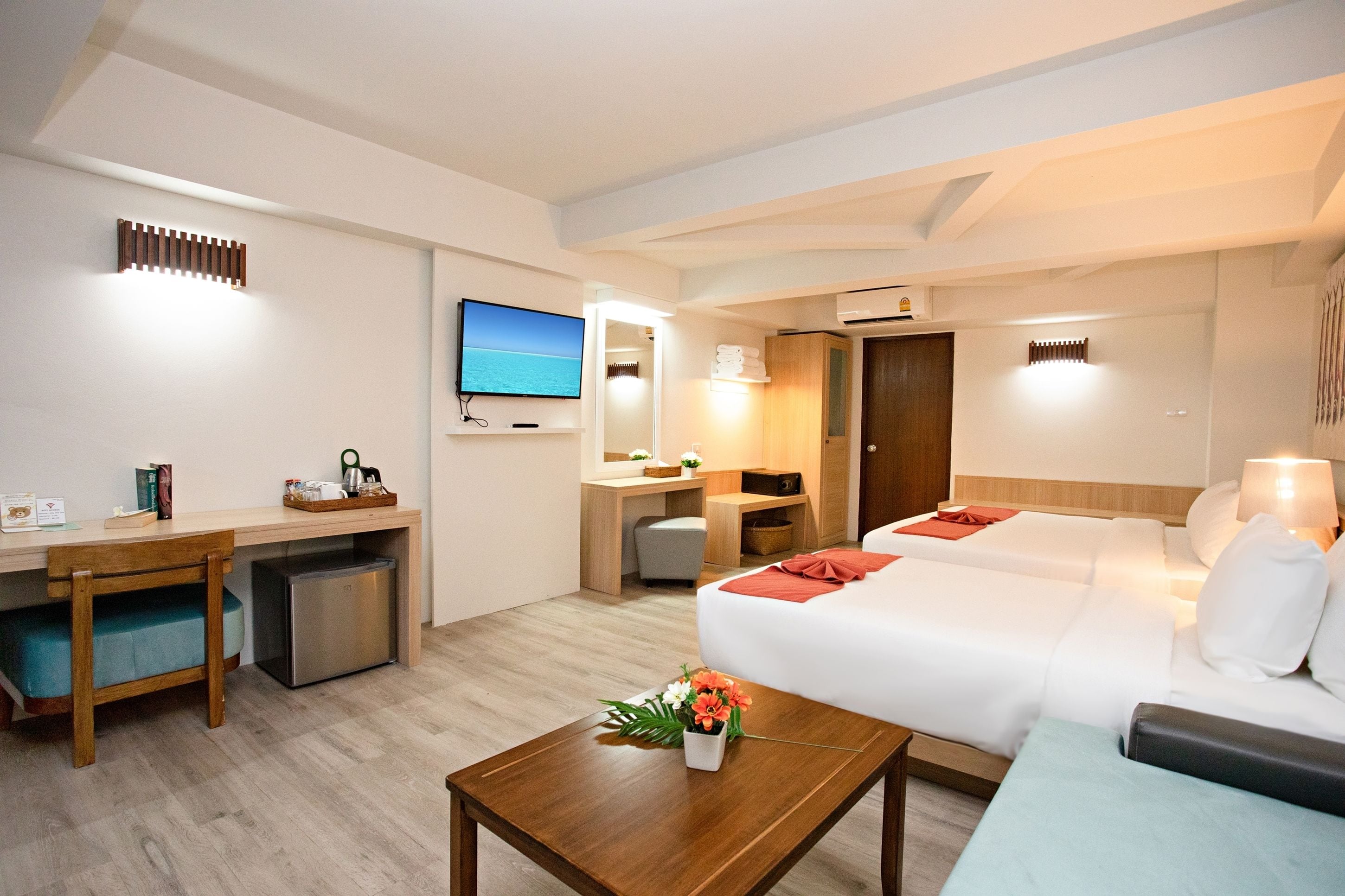 A hotel room with a bed, a desk, a TV, and a small kitchenette.