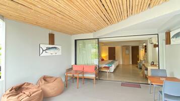 Un interior moderno con techo de bambú, una cama, una zona de comedor y sillones de tierno.