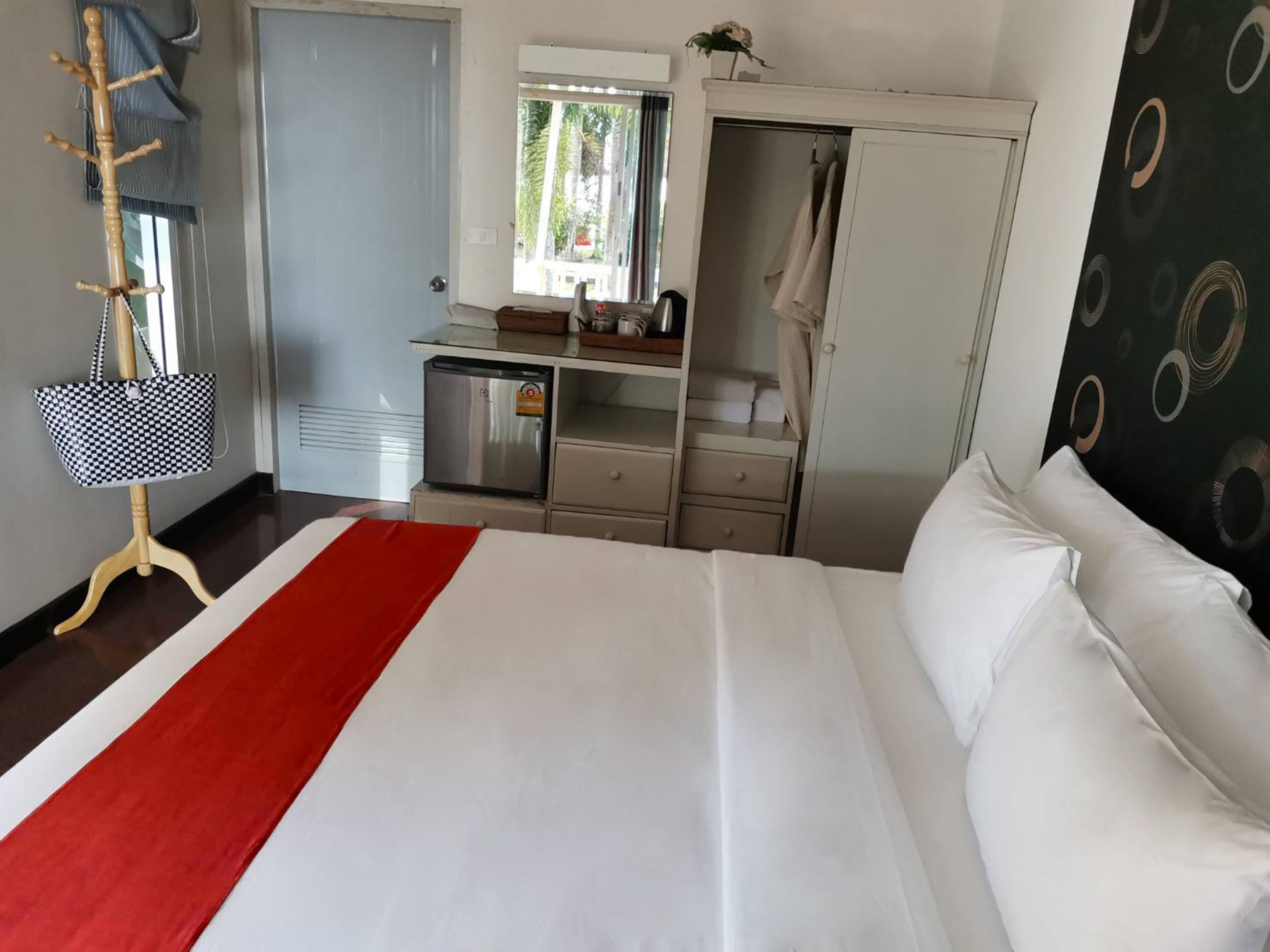 Et hotelværelse med seng, skrivebord, garderobe og knagerække.