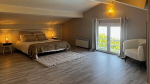 Un dormitorio con cama, lámparas de noche, un radiador, una ventana con cortinas y vistas a zonas verdes.