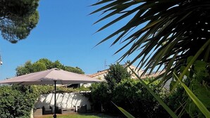 Una piscina con muelle de madera, sillas de descanso y una sombrilla.