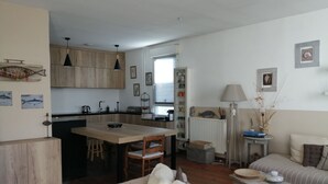 A cozy living room with a sofa and a dining area with a wooden table and chairs. - Charming apartment, everything on foot or by bike. Heart of Capbreton (Capbreton)