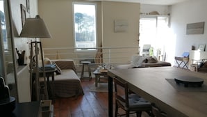 A cozy living room with a sofa, a dining table, and a lamp. - Charming apartment, everything on foot or by bike. Heart of Capbreton (Capbreton)