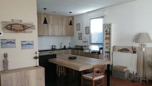 A compact kitchen with wooden cabinets, a dining table, and a small island. - Charming apartment, everything on foot or by bike. Heart of Capbreton (Capbreton)