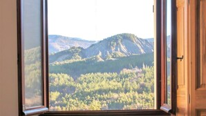 Quarto com uma janela grande que oferece vista para uma paisagem montanhosa.