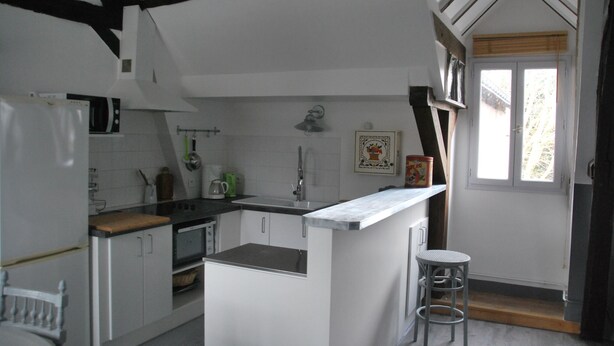 Una cocina con armarios blancos, una encimera de madera, un fregadero y una ventana con vistas al exterior.