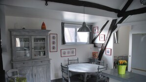Un comedor con mesa y sillas de madera, un armario con puertas de cristal y una ventana con cortinas.