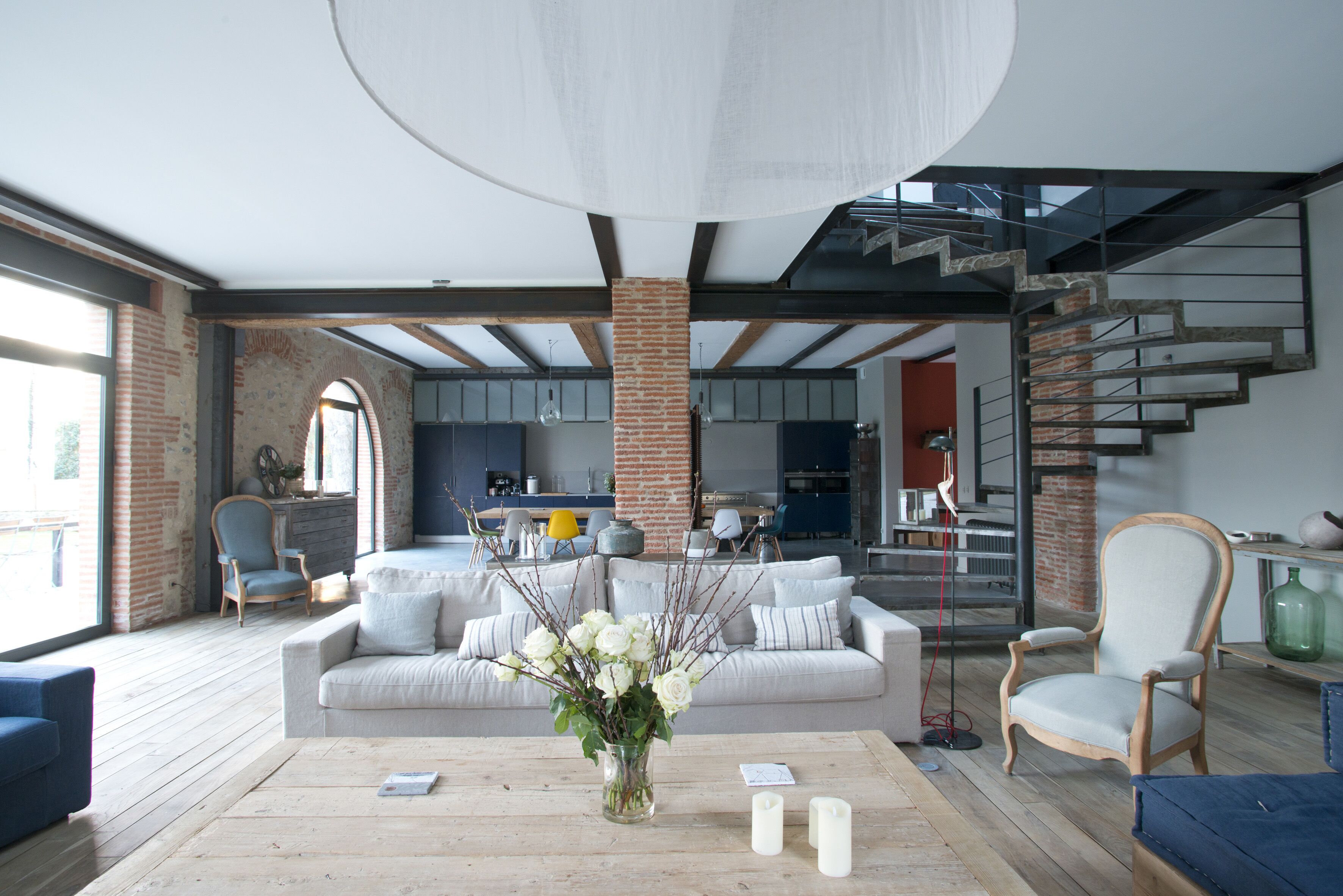 A modern living room with a sofa, a coffee table with candles, and a vase of flowers.