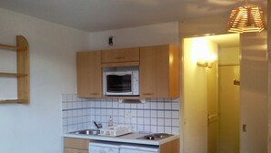 A compact kitchen with wooden cabinets, a microwave, a dishwasher, and a sink.
