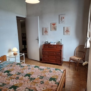 Ein Schlafzimmer mit Bett, Schminktisch, Stuhl und Wandbildern.