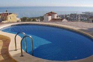 Ein Pool mit Metallgeländer, umgeben von einer gepflasterten Terrasse.