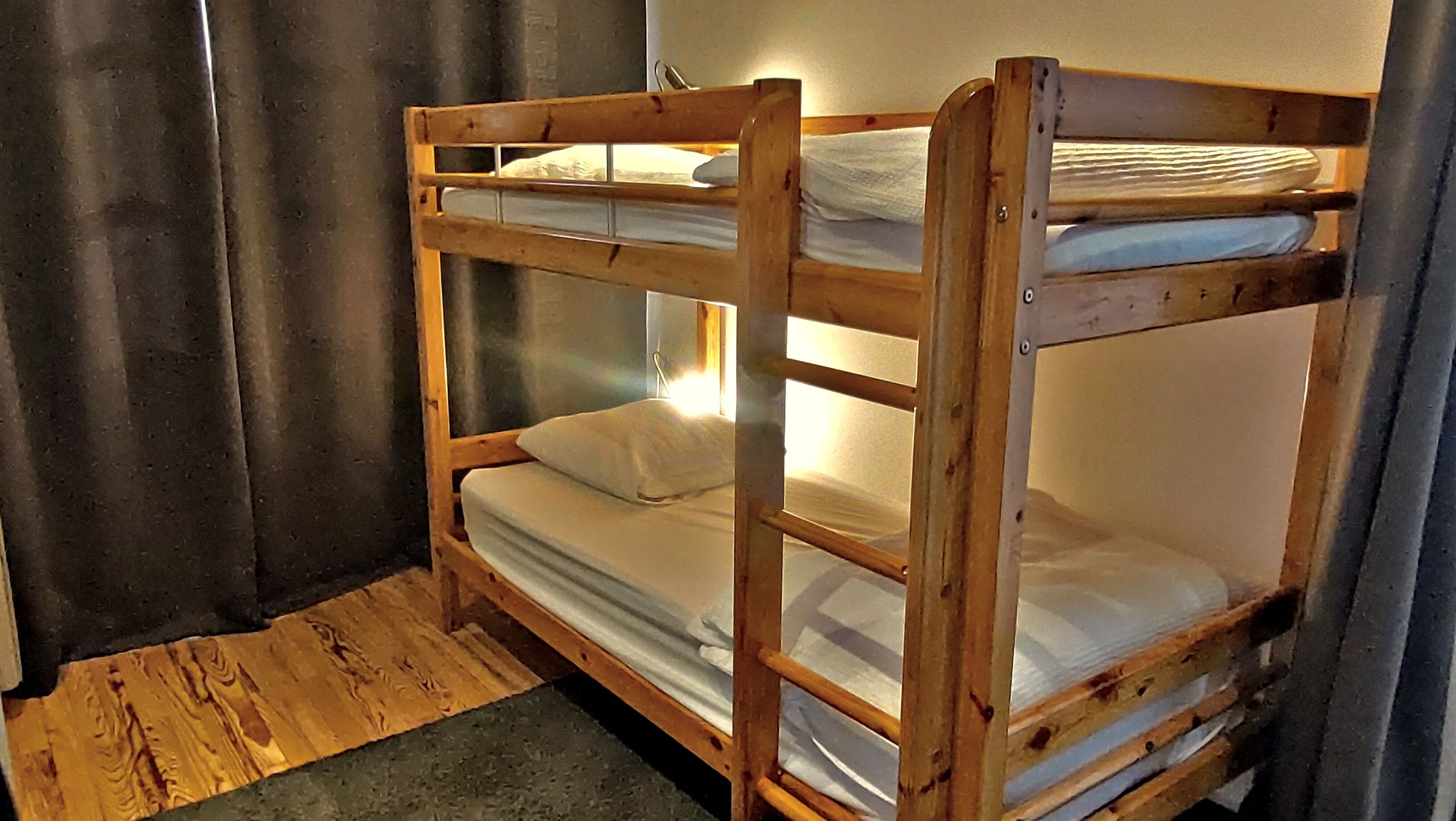 Une chambre avec un lit superposé, dont la structure est en bois et la literie est blanche.