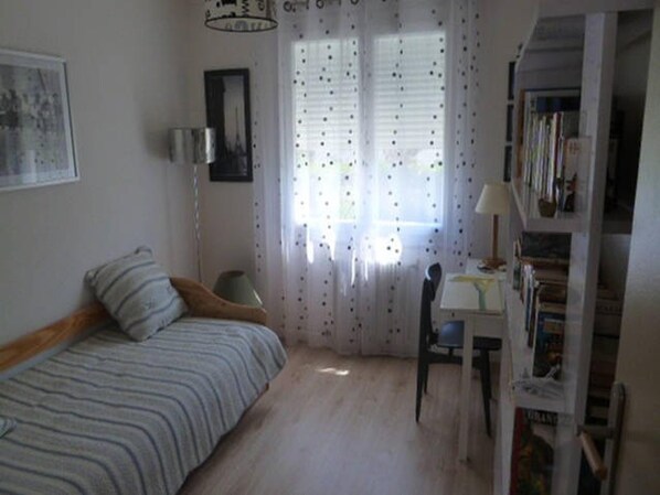 A bedroom with a bed, a desk, and a bookshelf.