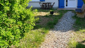 A two-story building with blue shutters, a gravel path leading to a wooden table and chairs, and a small garden area. - 50m² studio with garden near Toulouse (Baziège)