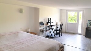 A bedroom with a bed, a desk with a chair, and a door leading to a balcony. - 50m² studio with garden near Toulouse (Baziège)