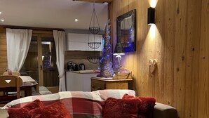 Una sala de estar acogedora con un sofá a cuadros, cojines rojos, un candelabro de vidrio y una pared de madera.