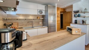 Una cocina moderna con encimera de madera, electrodomésticos de acero inoxidable y microondas integrado.