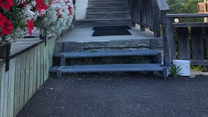 Una escalera de madera que conduce a un edificio con un letrero que dice "Le taufinguy" y una vista de un paisaje verde al fondo.