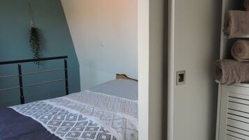 Une chambre à coucher avec un lit, une plante suspendue et une armoire contenant des serviettes.