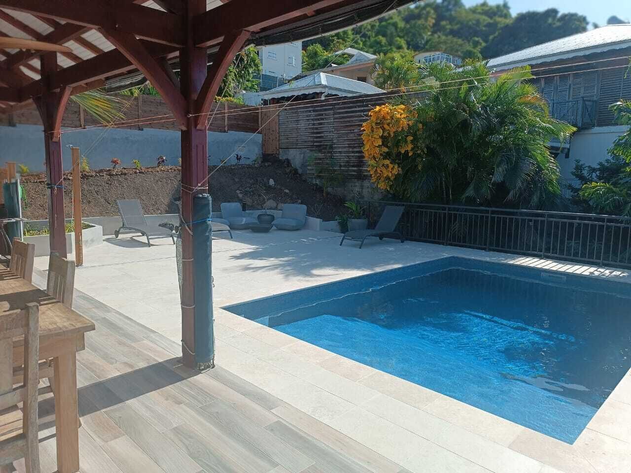 Una piscina con muelle de madera y sillas de descanso.