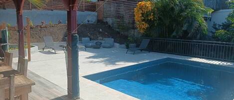 Una piscina con muelle de madera y sillas de descanso.