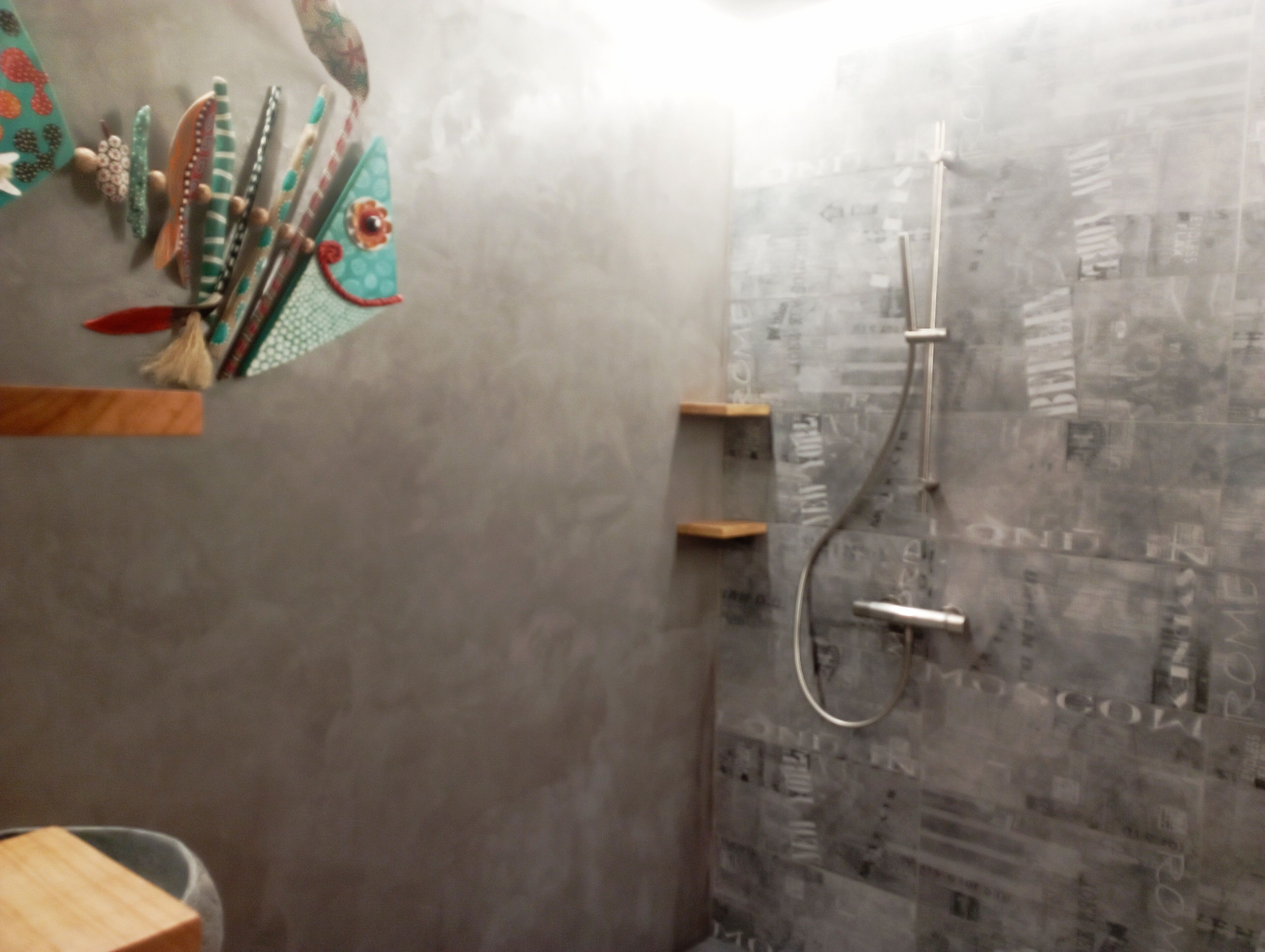 A bathroom with a shower, a towel rack with decorative items, and a wooden shelf.