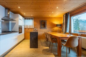 Une cuisine moderne avec des murs en bois, un îlot central et un coin repas avec des chaises.