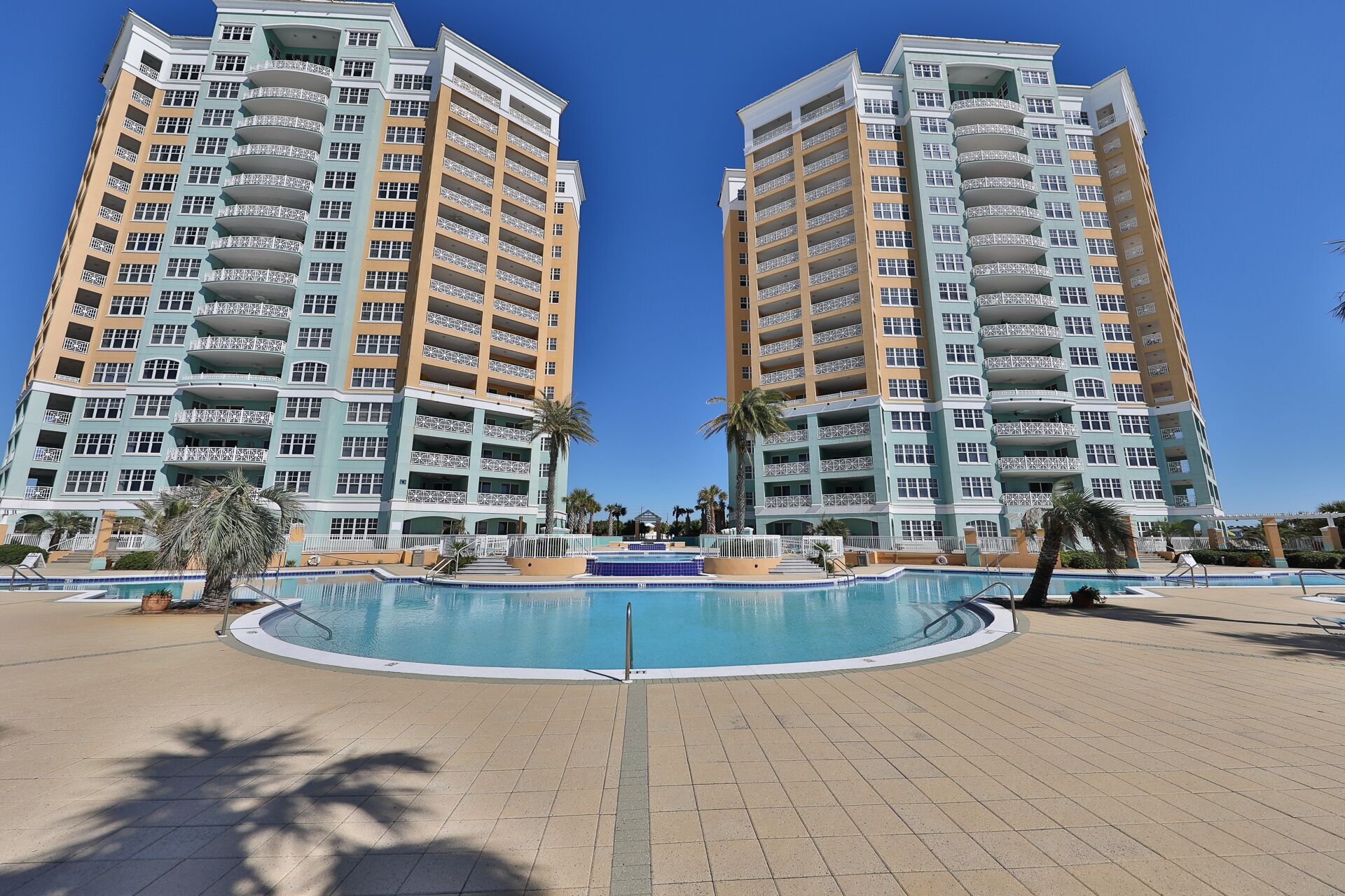 Un hôtel moderne à plusieurs étages, doté d’une piscine centrale et d’un espace extérieur bien aménagé.
