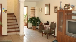 A living room with a staircase, a television, and a wooden cabinet. - Vacation Home: the Space, Privacy, Comfort of Your Own House! (San Salvador)