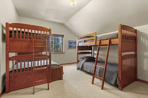 Um quarto com duas beliches, uma janela com vista e um quadro na parede.