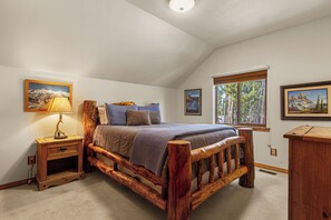 A bedroom with a wooden bed frame, a nightstand with a lamp, and two framed pictures on the walls.