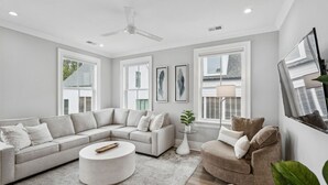 Un salon moderne avec un canapé d’angle, une table basse ronde et un fauteuil deux places.