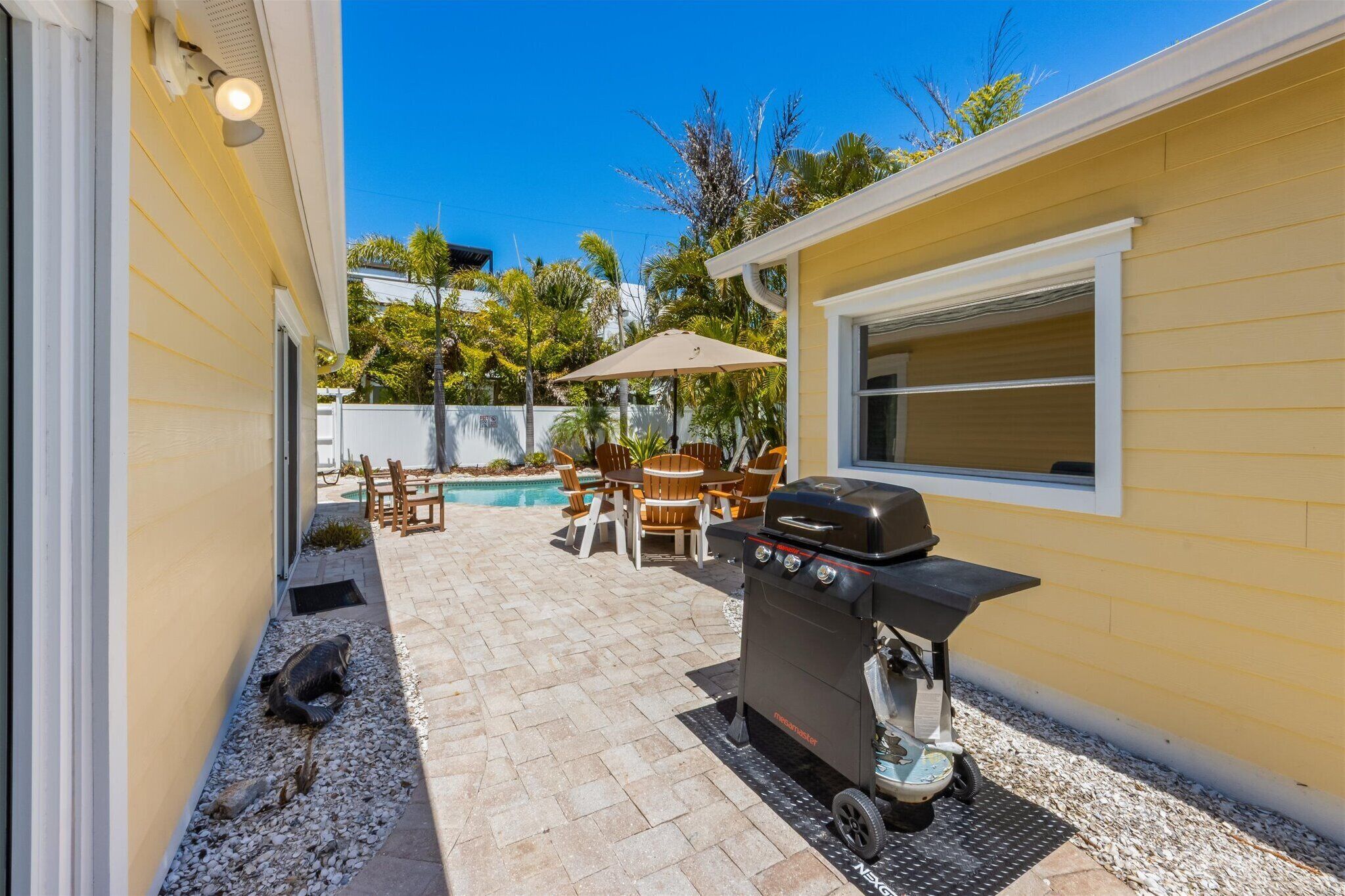 Un patio trasero con una parrilla, asientos exteriores y una piscina.