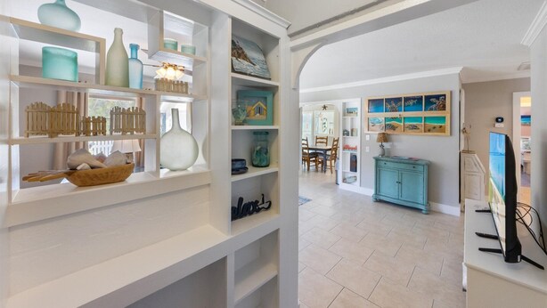 A spacious room with white walls, a wooden floor, and a dining area in the background. - Willow Cottage: Steps to the beach, heated pool, perfect location! (Anna Maria)