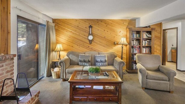 Una sala de estar acogedora con una pared de madera, un sofá, una mesa de centro, una estantería y una chimenea.