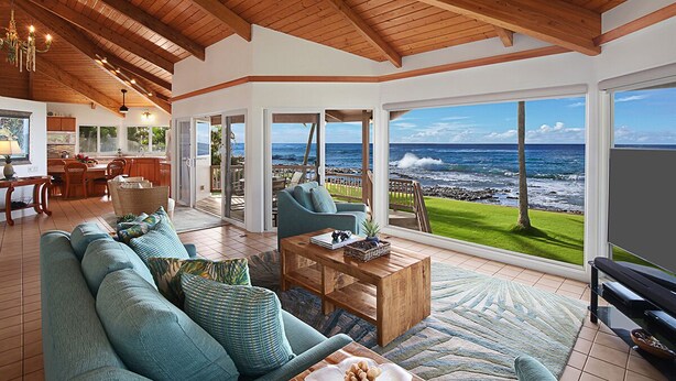 A spacious living area with a large window offering a view of the ocean. - Honu Lani | Private Oceanfront Home + Pool, Elevated Views & A/C (Koloa)