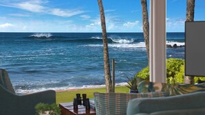 A room with a view of the ocean, featuring a window, a chair, and a small table with a plant. - Honu Lani | Private Oceanfront Home + Pool, Elevated Views & A/C (Koloa)