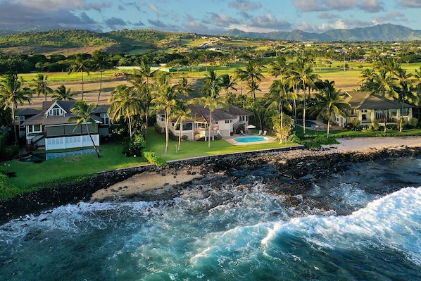 A coastal property with a swimming pool, multiple houses, and palm trees.
