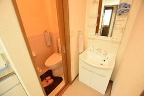 A compact bathroom with a toilet, sink, and shower area. - AIKAMU INN House (Osaka)