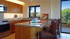 Una cocina moderna con armarios de madera, encimera de granito y una isla grande con taburetes de bar.