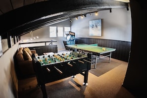 Relax and socialize in this inviting space, featuring a foosball table, ping pong table, and comfortable seating area.