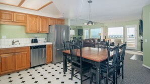 A modern kitchen with wooden cabinets, stainless steel appliances, and a dining area with a wooden table and chairs. - San Diego County Oceanfront 3 bedroom-heated pool/jacuzzi. Complex on the sand (Imperial Beach)