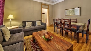 Una sala de estar con sofá, mesa de centro y mesa de comedor con sillas.