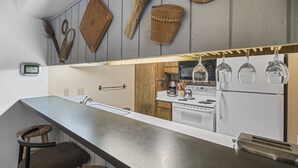 A modern kitchen with a long countertop, wooden stools, and a stove. - Sunshine Village 167 (Mammoth Lakes)