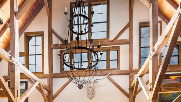 A spacious room with a high ceiling, wooden beams, and large windows. - Designer Barnhouse located just 8 minutes from Main St on Private Gated Ranch (Fredericksburg)