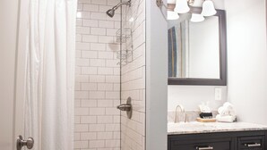 Une salle de bain avec une douche, un meuble-lavabo avec un miroir et un porte-serviettes.