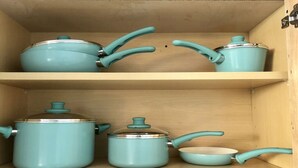Une étagère en bois sur laquelle sont rangés des ustensiles de cuisine, notamment des casseroles et des poêles.