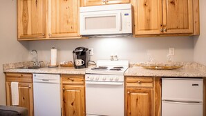 Une cuisine équipée d’armoires en bois, d’un four à micro-ondes, d’une machine à café, d’une cuisinière, d’un lave-vaisselle et d’un réfrigérateur.
