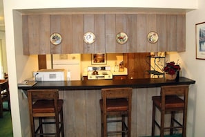Kitchen area with central island, microwave, stove, and utensils.